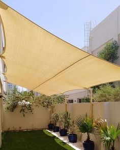 an outdoor area with grass, potted plants and a large shade sail