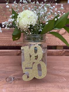 a mason jar filled with flowers on top of a wooden table