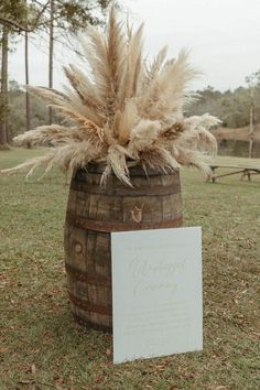 a wooden barrel with some dry grass in it and a sign on the ground next to it