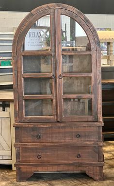 an old wooden cabinet with glass doors on the front and bottom, in a store