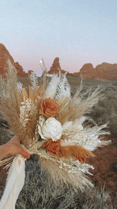 a person holding flowers in the desert at sunset