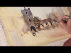 a person is painting an old building with watercolors on the paper and using a brush