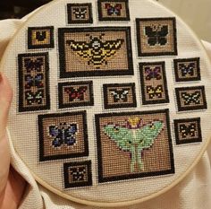 someone is holding up a cross stitch project