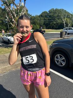 a girl is standing in the parking lot with her medal