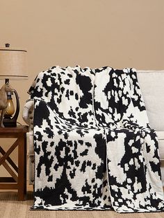 a black and white blanket sitting on top of a couch next to a table with a lamp