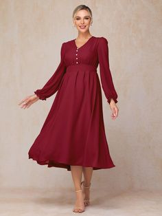 a woman wearing a red dress with long sleeves and buttons on the waist, standing in front of a beige background