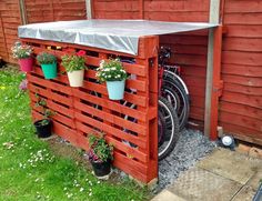 a bike is parked in front of a red fence with potted plants on it