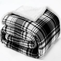 two blankets folded on top of each other in black and white checkered fabric, one with a sherpam over it