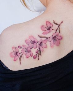 a woman's upper back tattoo with pink flowers on her left shoulder and chest