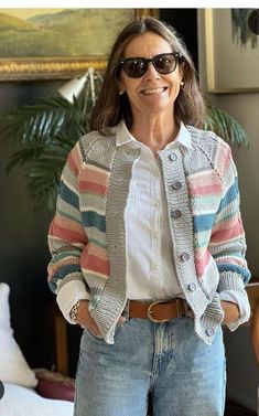 a woman standing in front of a painting wearing sunglasses and a striped cardigan sweater