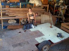 a woman standing next to a table in a room filled with wooden planks and plywood