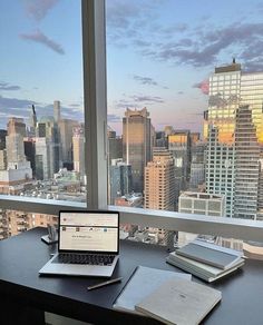 an open laptop computer sitting on top of a desk in front of a large window