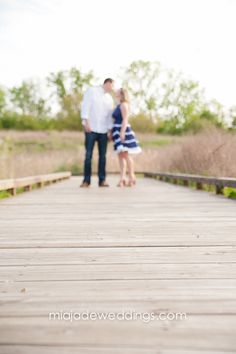 a man and woman standing on a wooden bridge