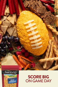 a football shaped cheese ball surrounded by crackers, grapes, carrots and other foods