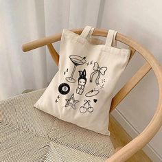 This 100% cotton tote bag is perfect for everyday wear. It's durable and will last for years. The bag features 20" handles (made from the same canvas), making it easy to carry even with a week's worth of shopping. * 100% cotton canvas * Heavy fabric Sizing: * 15 inches x 16 inches Care Instructions: * Hand wash only if needed Estimated Delivery Times:  Canada:  * Standard: 4-16 days  USA:  * Standard: 4-16 business days * Economy: 4-8 business days  International: * Standard: 10-30 business days Minimalist Coquette, Coquette Graphic, Y2k Tote Bag, Totes Ideas, Bag Y2k, Canvas Bag Design, Bag Minimalist, Printed Canvas Tote Bag, Cute Canvas