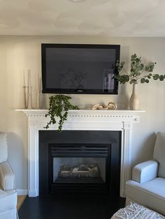 a flat screen tv mounted above a fire place in a living room with white furniture