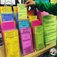 a young boy standing in front of a pile of colorful binders with writing on them