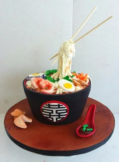 a cake made to look like a bowl of food with chopsticks sticking out of it