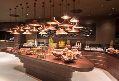 a buffet with lots of food and lights hanging from it's ceiling above the counter