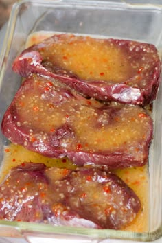 two raw meats in a glass dish with seasoning on top, ready to be cooked