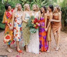 a group of women standing next to each other on a brick floored walkway with palm trees in the background