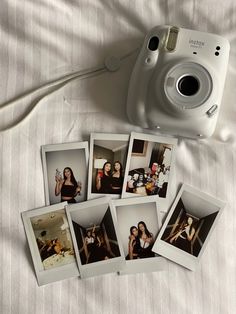 several polaroid pictures are placed next to a camera on a bed with white sheets