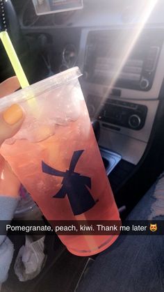 a person holding a drink in their hand while sitting in the backseat of a car