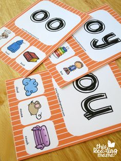 four orange and white cards with black letters on them sitting on top of a wooden table