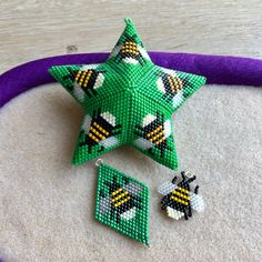 a green beaded star next to two earrings on top of a purple hoop bag