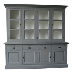 a gray china cabinet with glass doors and drawers on the top, next to a stair case