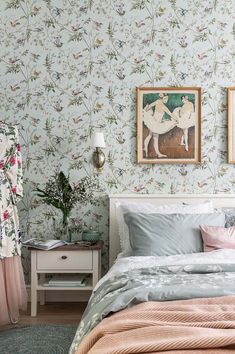 a bedroom with floral wallpaper and bedding in pastel colors, including pink