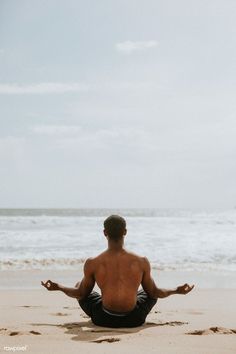 a man sitting on the beach doing yoga