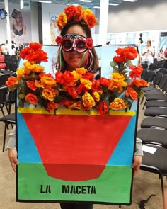 a woman is holding up a sign with flowers in the shape of a flower pot