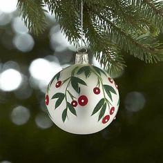 a white ornament hanging from a tree with red berries and green leaves on it