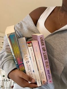 a woman holding several books in her hands