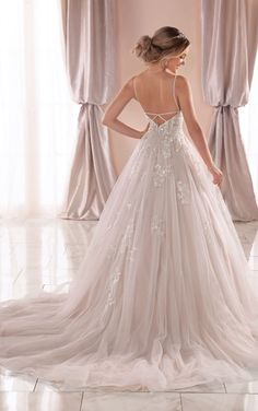 a woman in a wedding dress looking back at the camera while standing in front of curtains