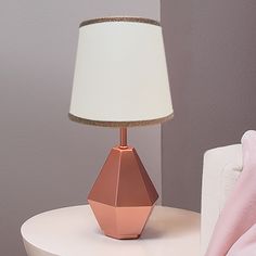 a pink lamp sitting on top of a table next to a white couch and chair