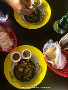 three plates filled with different types of food on top of a black table next to drinks and condiments