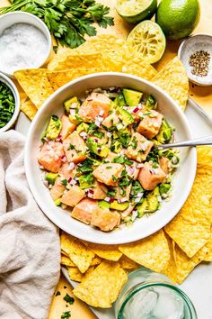 a white bowl filled with fish and guacamole surrounded by tortilla chips