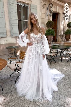 a woman standing in front of a building wearing a white dress