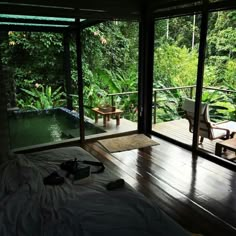 a bed sitting in a bedroom next to a lush green forest filled with lots of trees