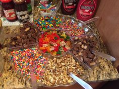 there are many different types of candy in the bowl on the counter top, including candies and nuts