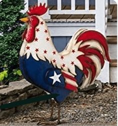 a rooster statue is standing in front of a house with an american flag on it's tail