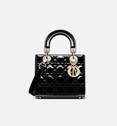 The Lady Dior bag epitomizes Dior's vision of elegance and beauty. Sleek and refined, the timeless style is crafted in black patent calfskin with Cannage stitching, creating the instantly recognizable quilted texture. Pale gold-finish metal D.I.O.R. charms further embellish its silhouette. The small Lady Dior bag features a thin, removable leather shoulder strap and can be carried by hand or worn crossbody.. Lady Dior Handbag, Small Lady, Christian Dior Couture, Dior Handbags, Dior Couture, Wallet Pouch, The Lady, Lady Dior Bag, Lady Dior