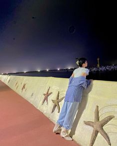 a woman standing on the side of a wall next to starfish and sea stars