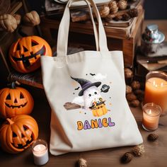 a white tote bag sitting on top of a table next to candles and pumpkins