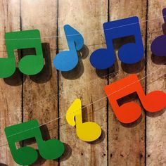 colorful wooden music notes hanging from clothesline on wood planked wall with string and pegs