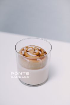 a glass filled with some kind of food on top of a white table next to a wall