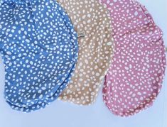 three different colored polka dot hats on a white surface with blue, pink and brown dots