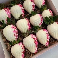 there are strawberries in the box with pink flowers on them, and green leaves